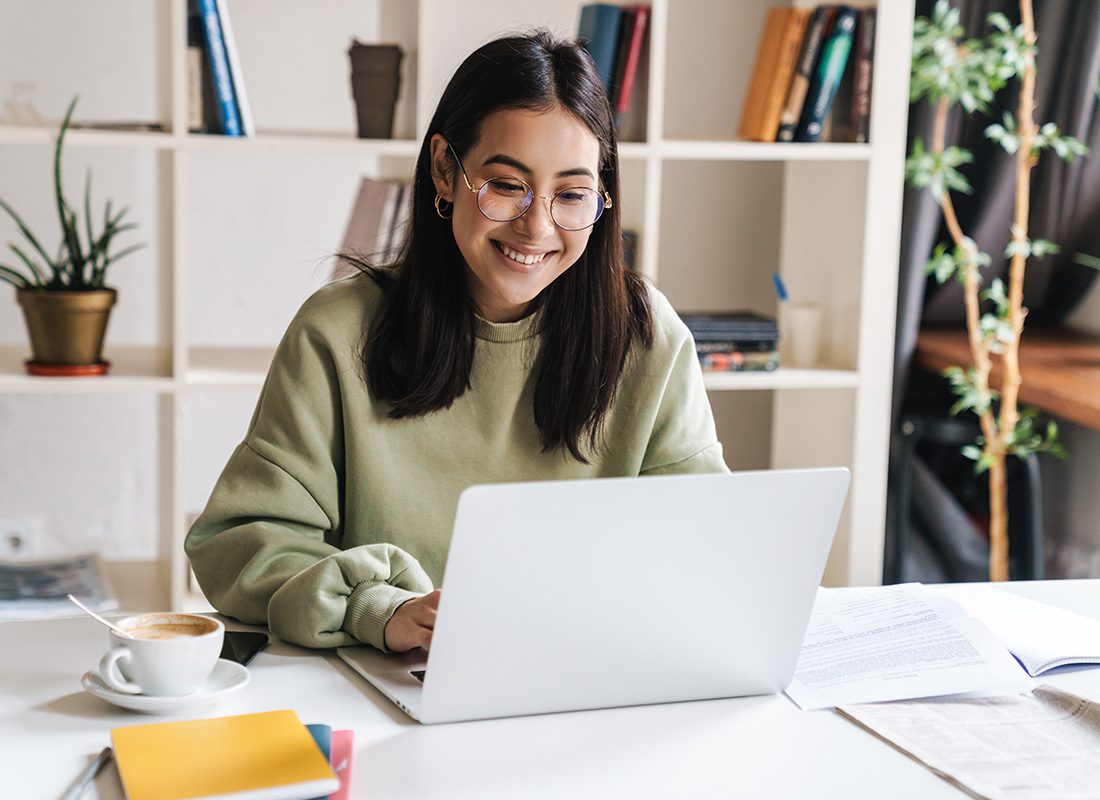 Blog - Woman Smiling and Working on Her Open Laptop in a Modern Home